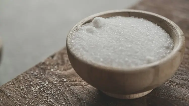 A small wooden bowl of salt on a wooden work surface